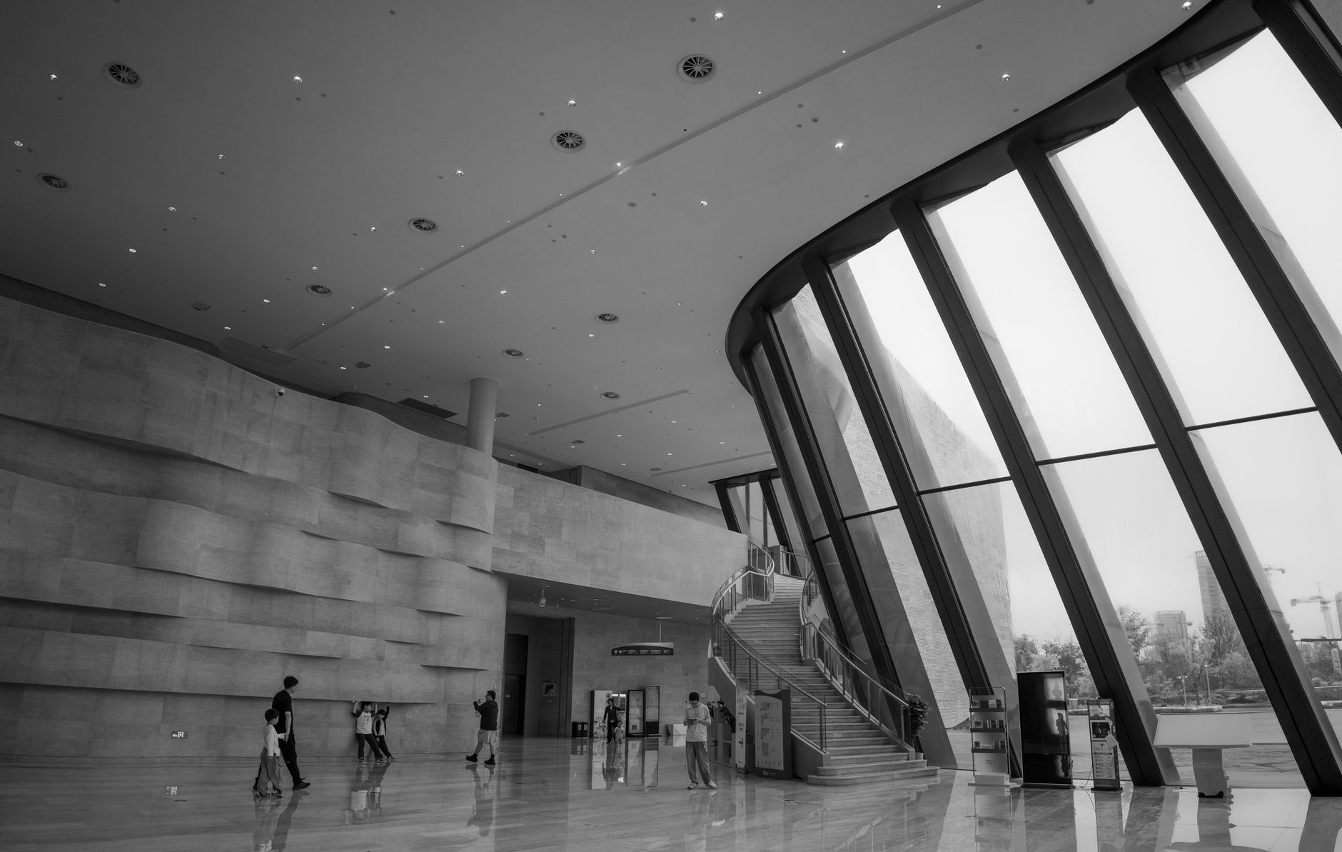 A modern interior with high ceilings and a curved stair.
